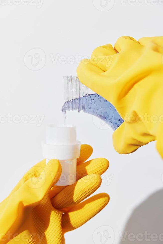Woman in yellow gloves holding a bottle of hand sanitizer with a yellow cap. a female person wearing photo