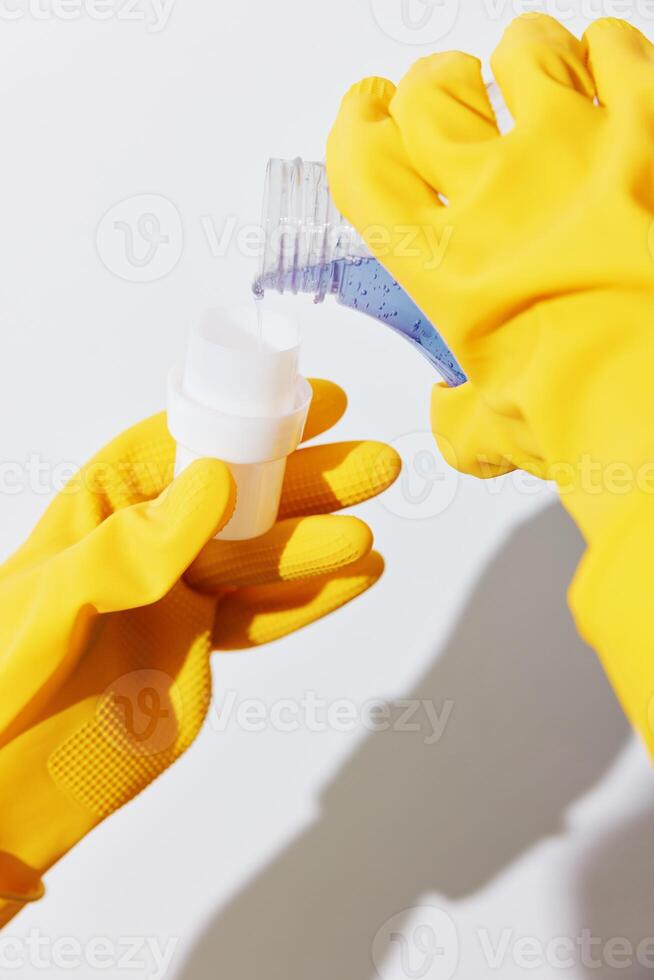 Woman in yellow gloves holding hand sanitizer bottle with yellow sponge. sanitizing and cleaning photo