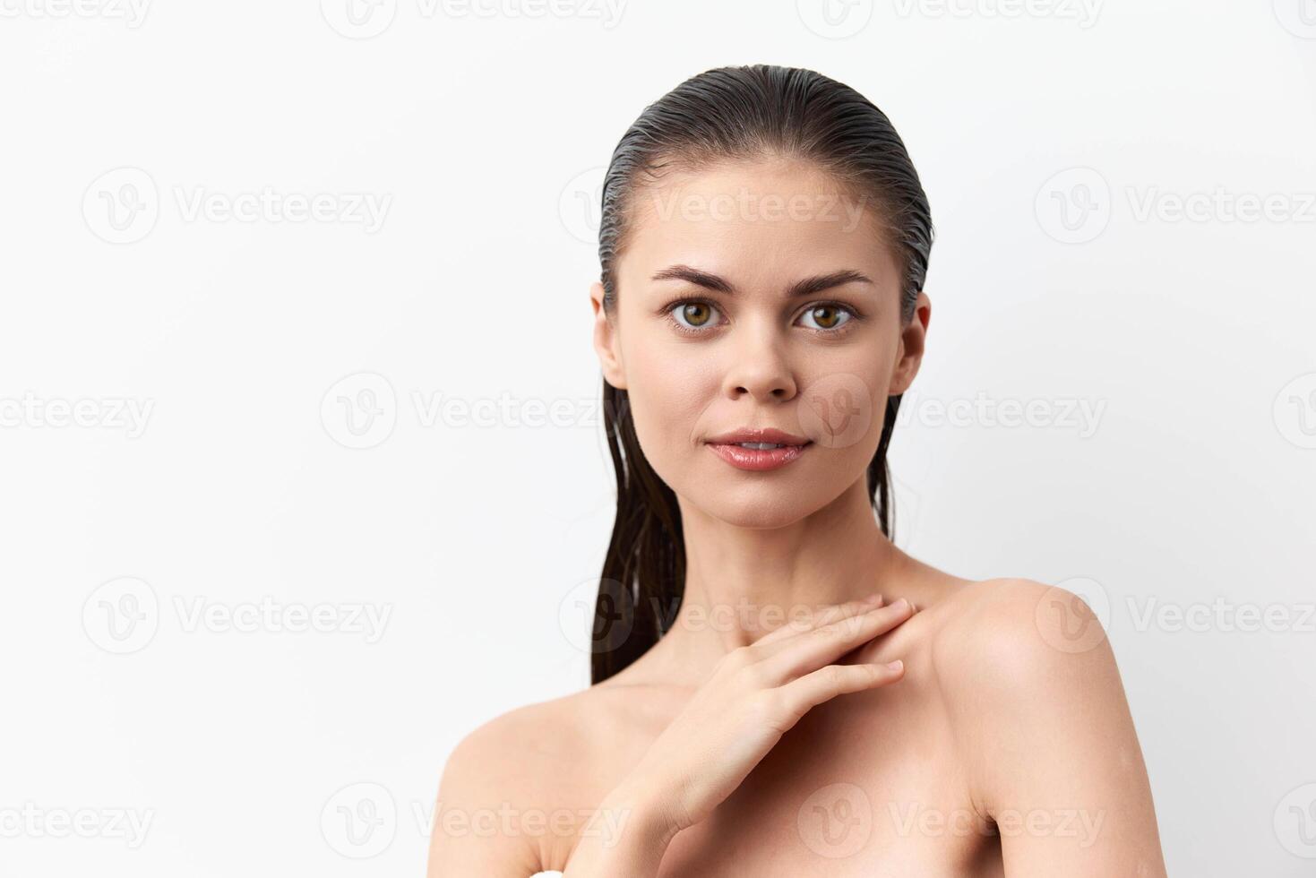 Portrait of a young woman after a shower with a wet head on a white background, looking into the photo