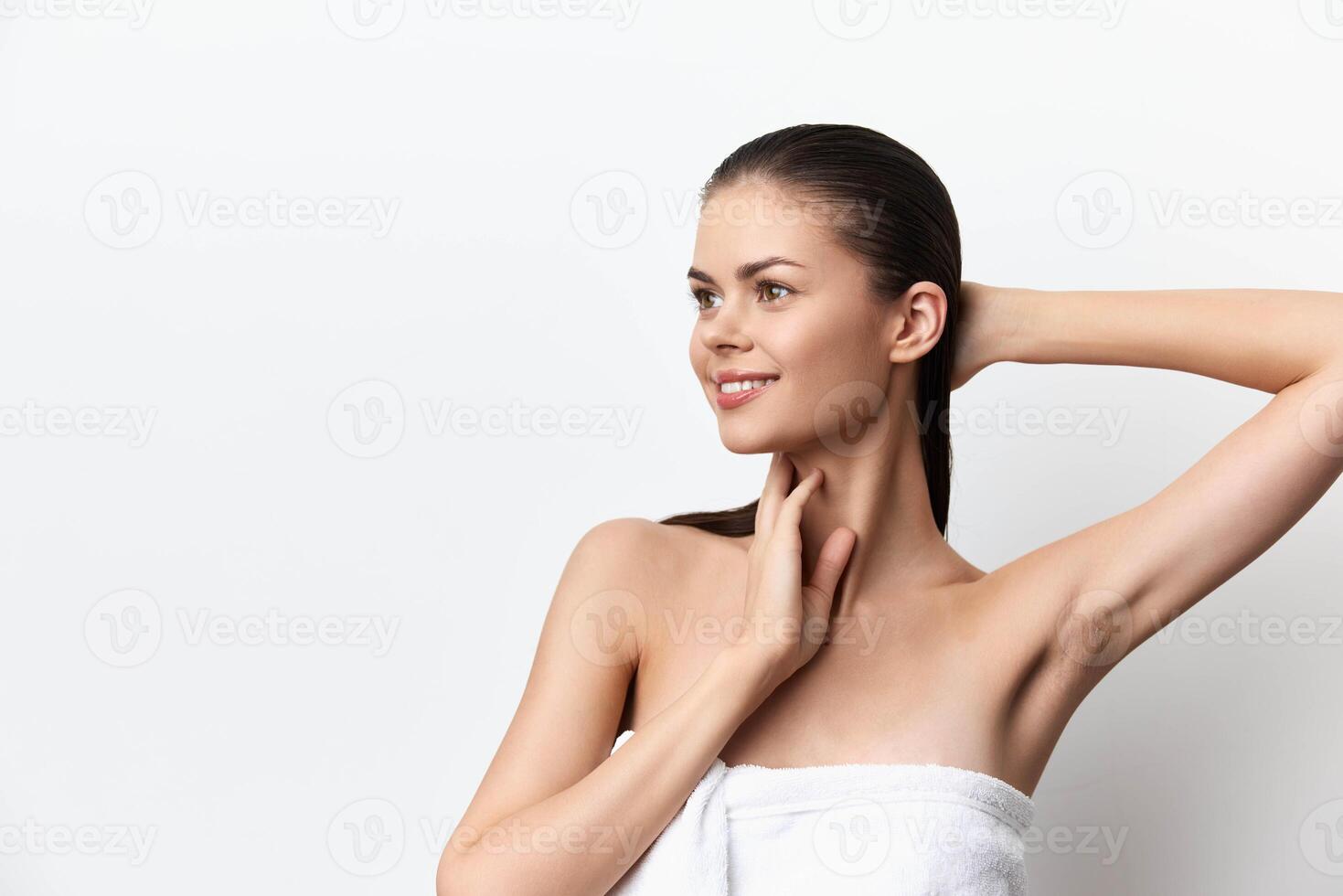 This image features a beautiful woman with glowing skin, smiling softly while holding her neck She photo