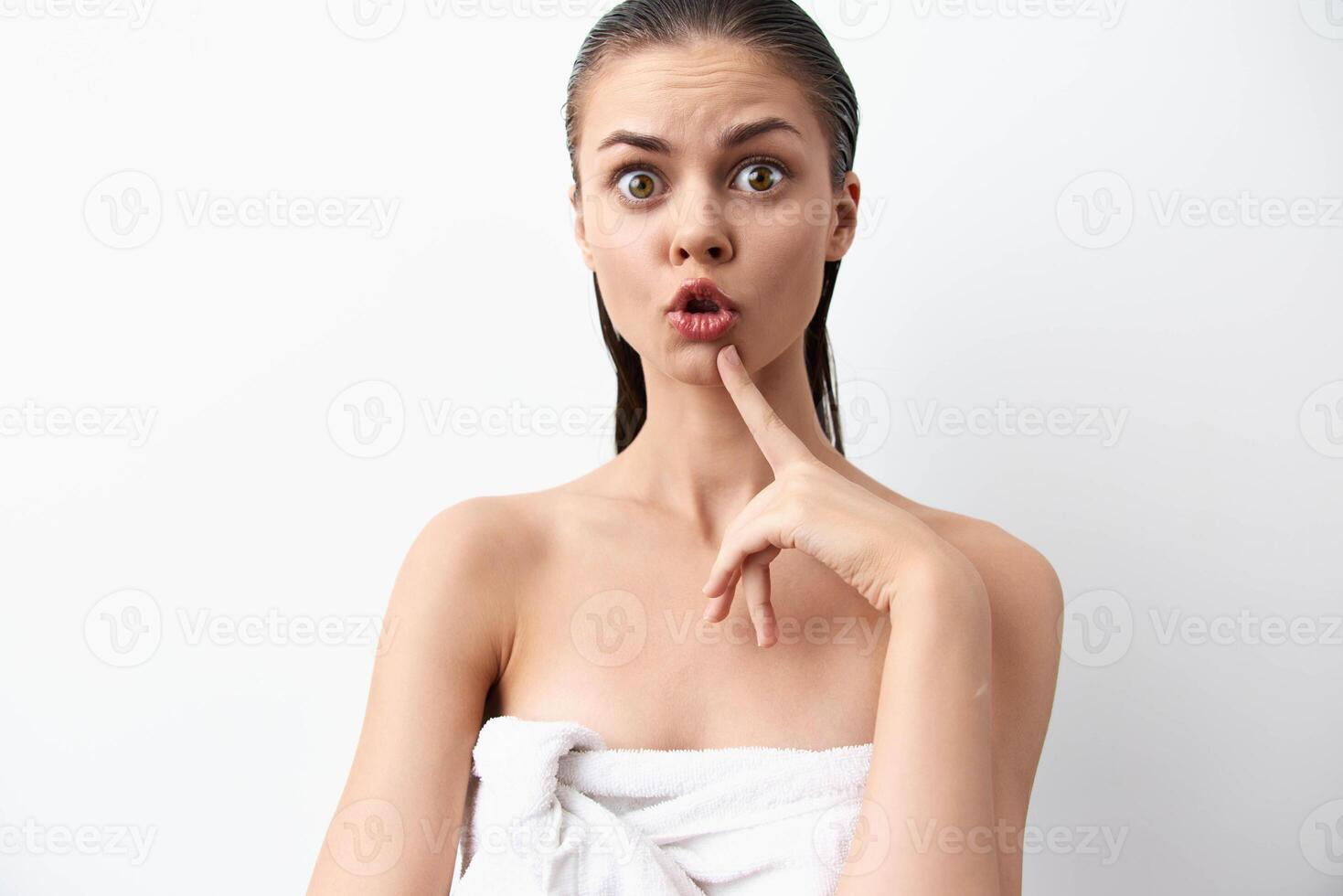 surprised expression of a young woman with a towel on her body and finger on her lips, set against a photo