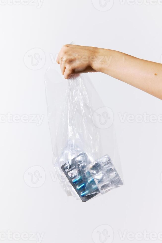 Hand holding full plastic bag of pills on white background. photo