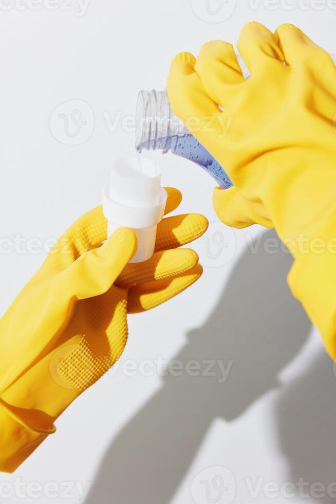 Yellow rubber gloved hands holding bottles of hand sanitizer in a clearing. photo