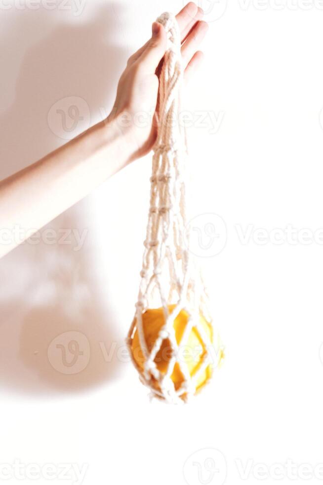 Hand holding white net bag with oranges, isolated on white background. photo