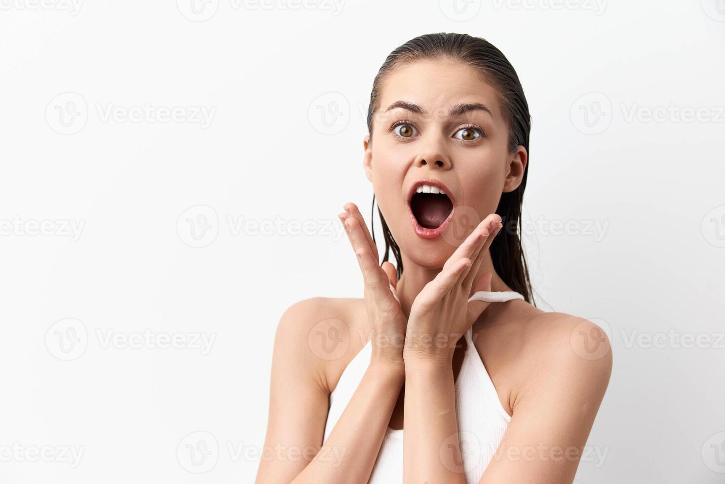 A surprised and joyful young woman with wet hair, showcasing an expressive face on a white photo