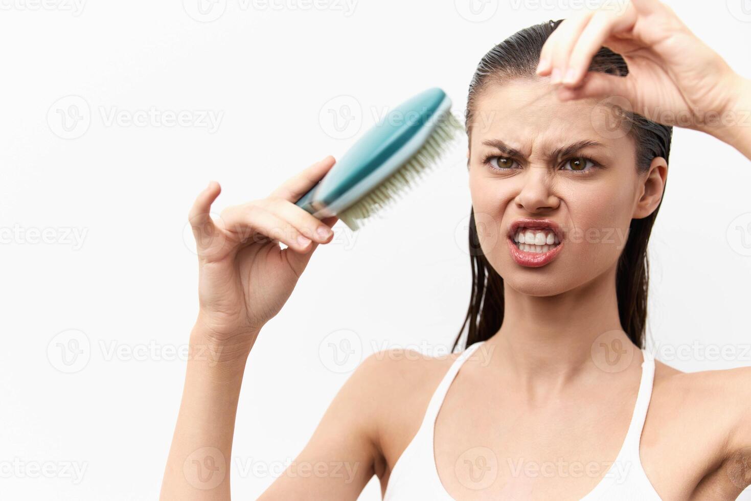 frustrated woman with a hairbrush displaying an unhappy expression, struggling with tangled hair She photo
