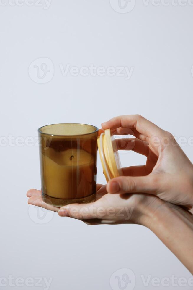 Person holding a candle with two lids on top and bottom. photo