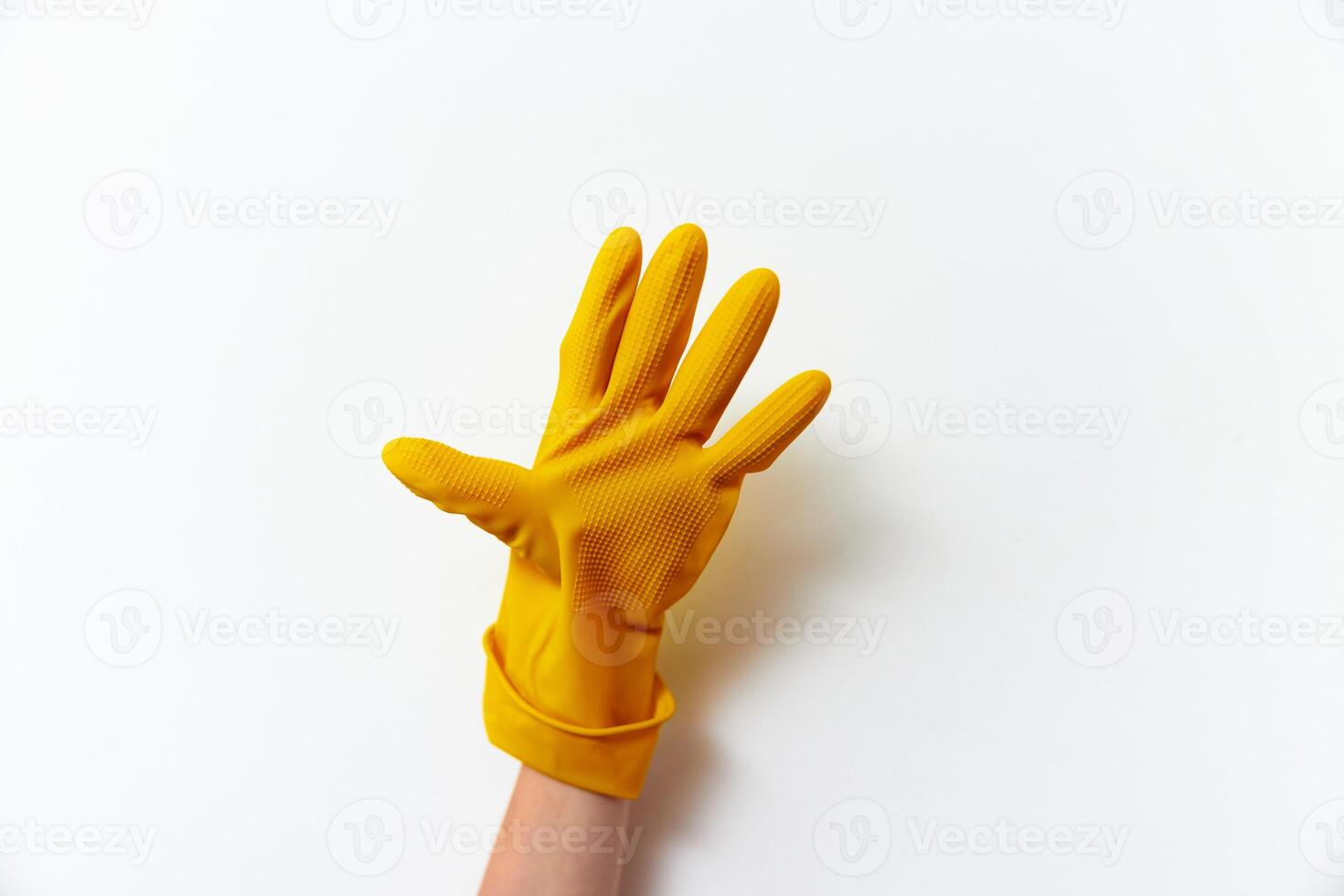 Yellow rubber gloves on white background. one hand wears a yellow glove, while another glove is photo