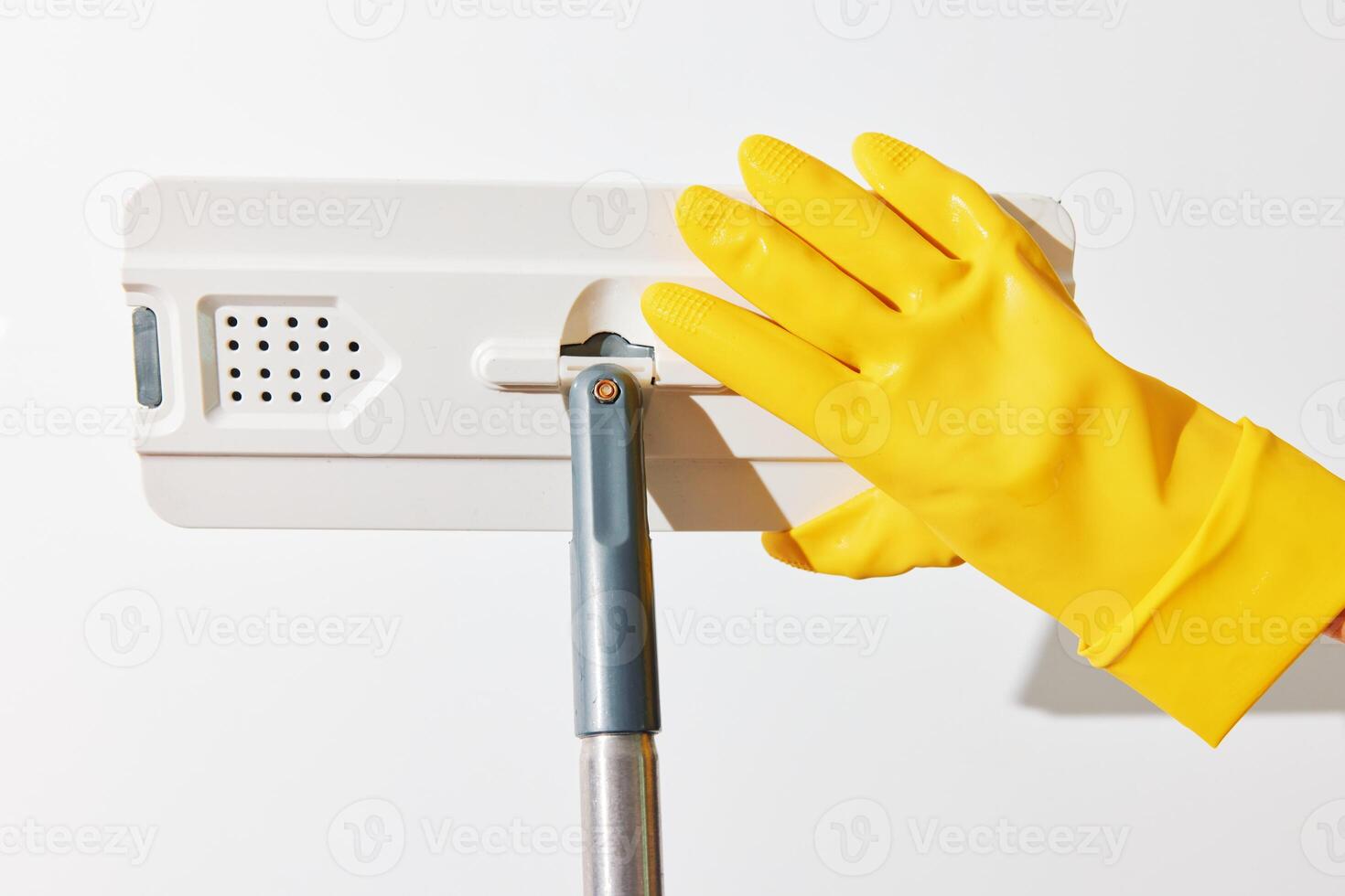 Cleaning service concept - woman in yellow gloves holding a mop in front of a white wall with a sign photo