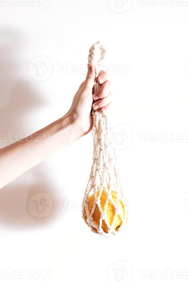 Rope bag with orange inside held by person on white background. photo