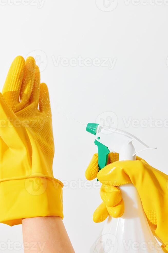 Two women in rubber gloves holding spray bottles with green and yellow nozzles on a white background photo