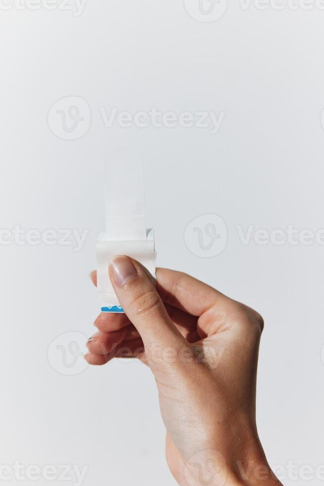 Hand holding small white object with copy space on white background. photo