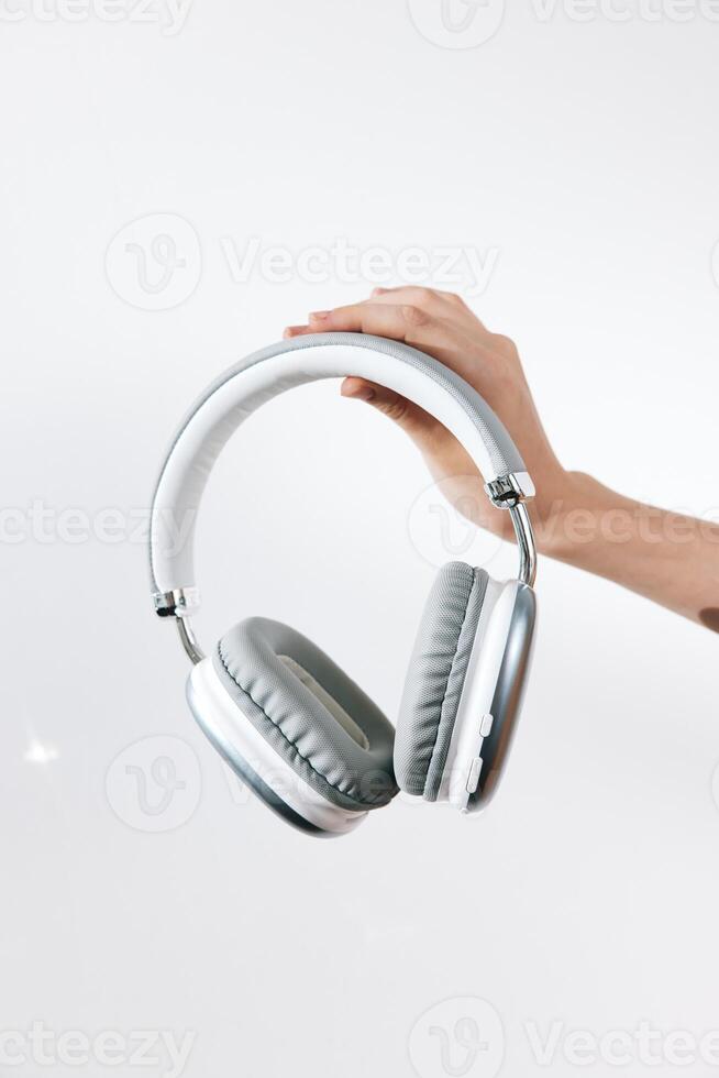 Hand holding headphones on white background with copy space in the middle. a close-up shot of a photo