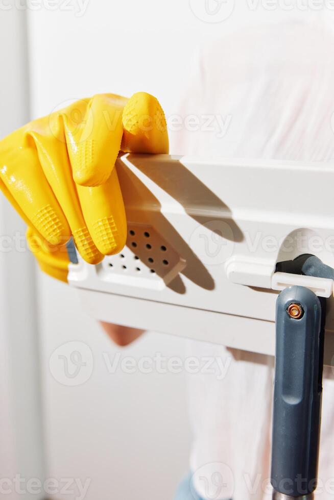 Woman in yellow gloves holding metal piece with paper near other paper pieces. a concept image of a photo