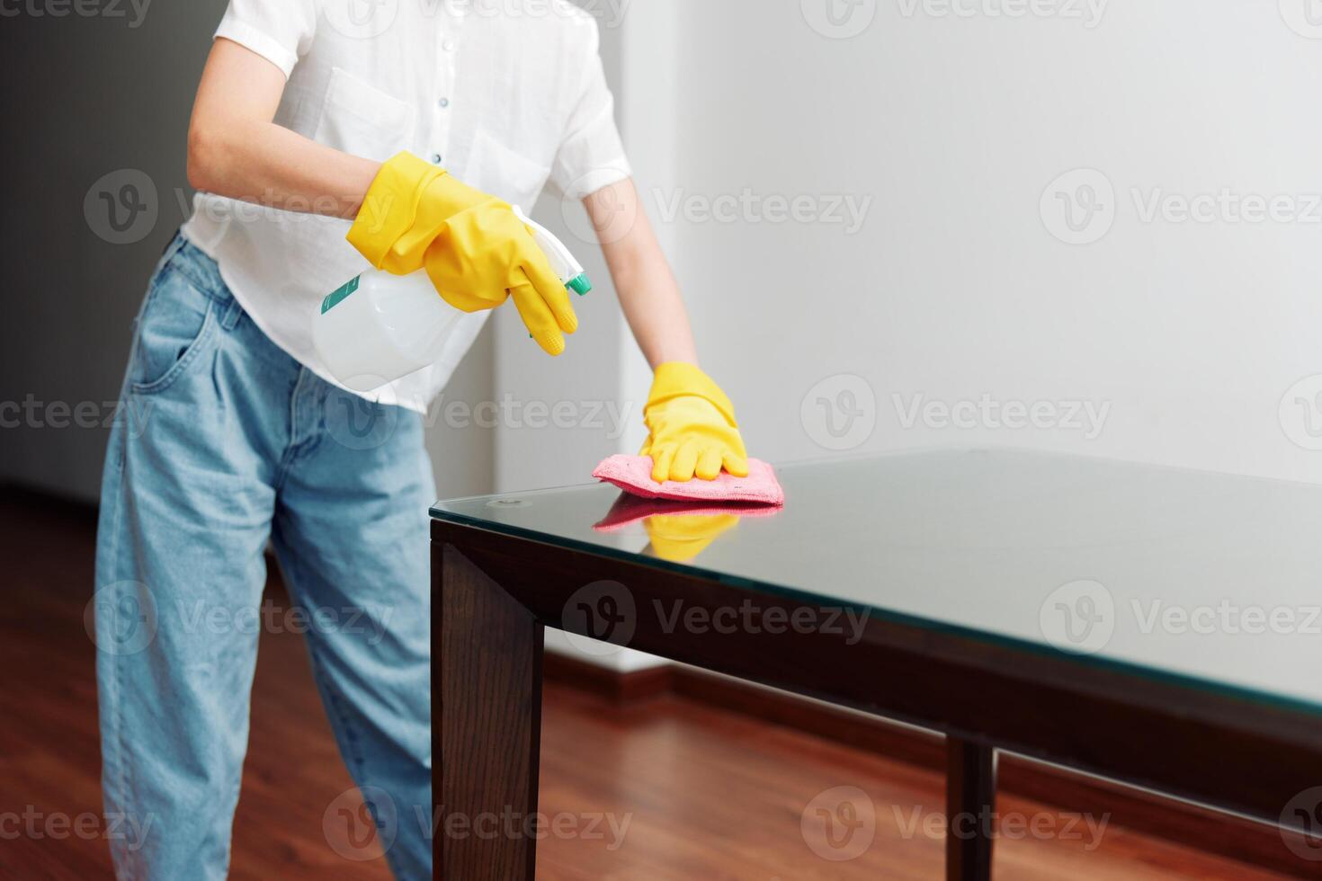 Woman cleaning glass table with mop and bucket of water in background. photo