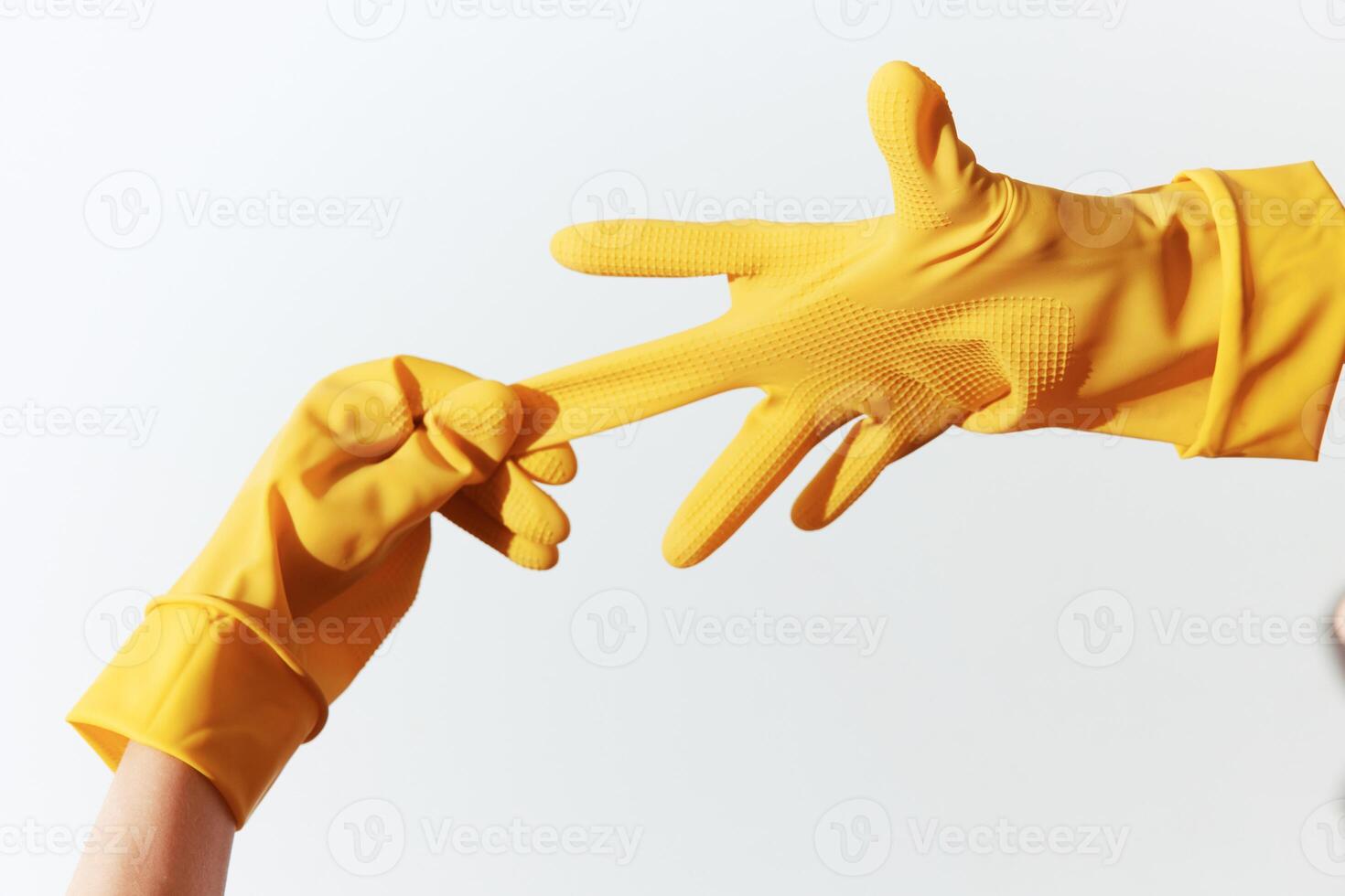Two individuals wearing yellow rubber gloves reaching out to each other on a white background. photo