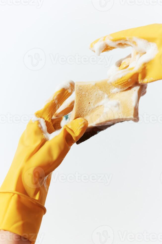 Yellow rubber gloves holding soap and sponge on white background. bright and colorful cleaning photo
