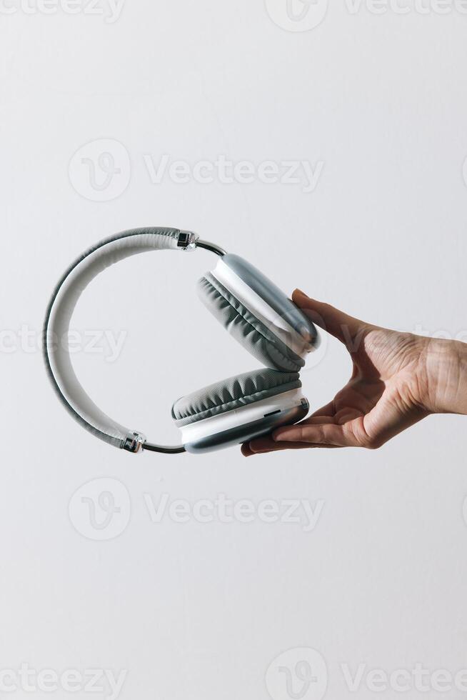Headphones held by person on white background with copy space in the middle of the image. photo