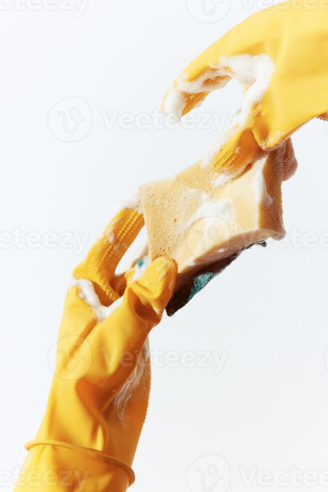 Person in yellow rubber gloves holding soap and sponge on white background. a conceptual image of photo