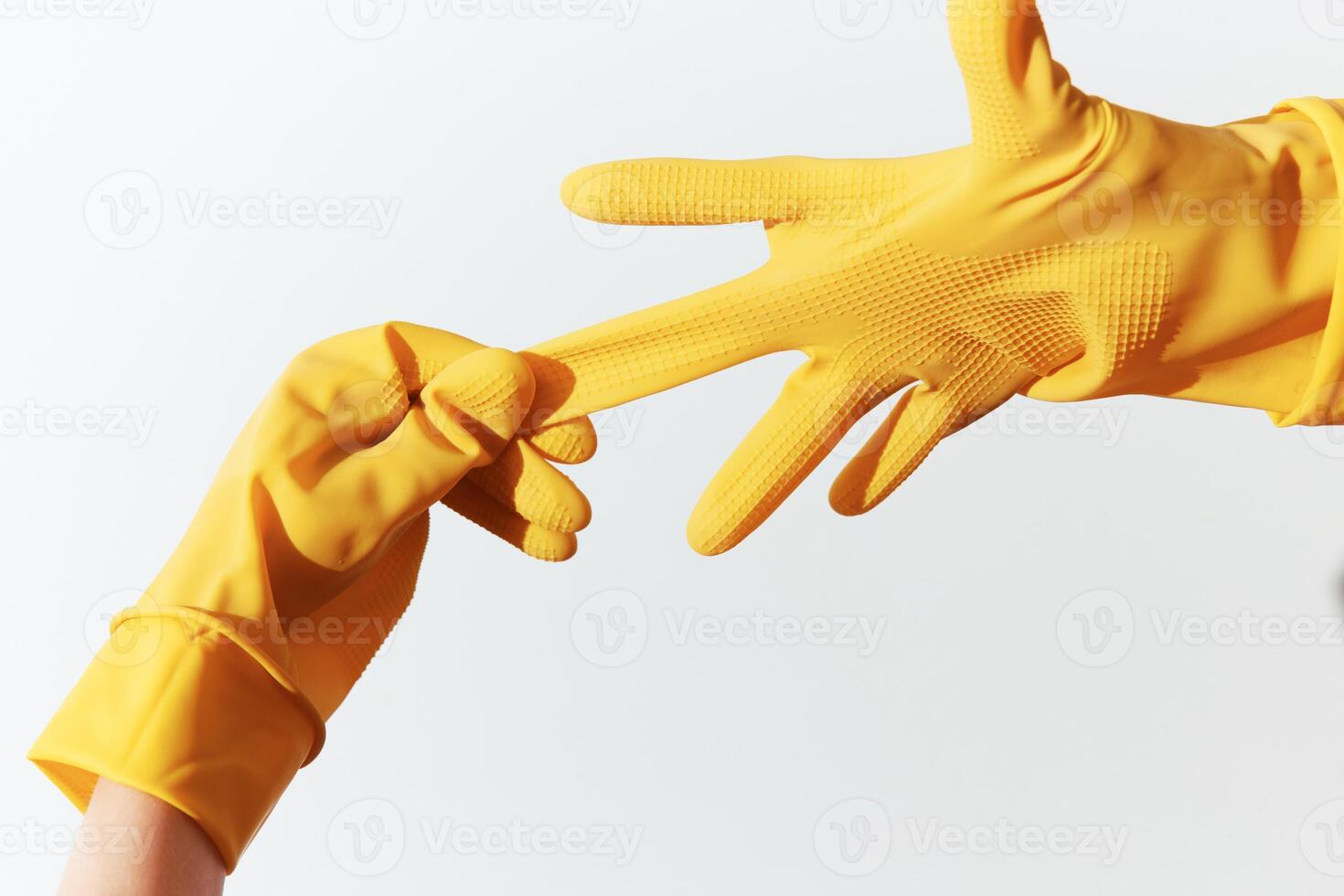 Two individuals wearing yellow rubber gloves reaching out to each other in a close-up shot. photo