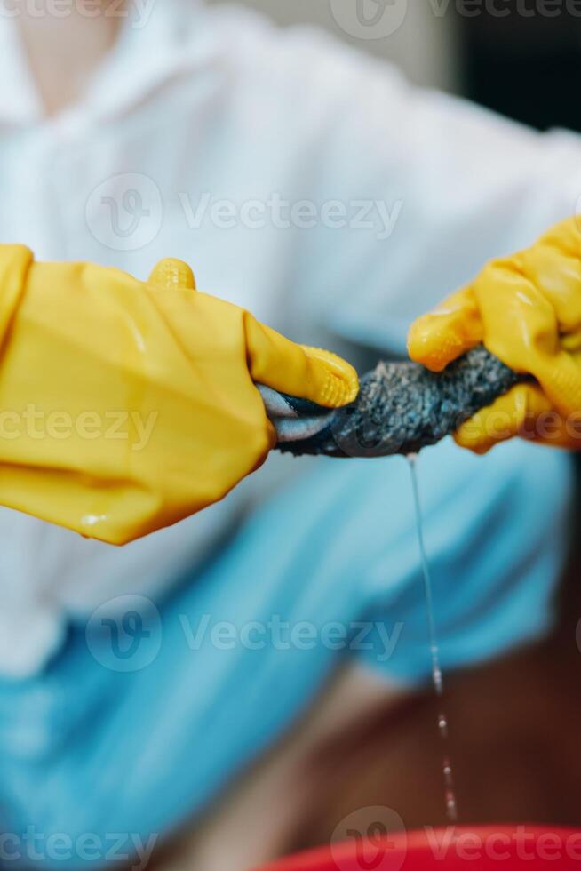 Man in yellow gloves holding a fish while sitting at a wooden table with a red bowl. photo