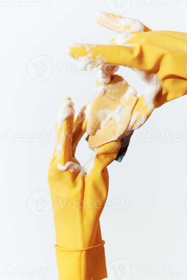 Yellow rubber gloves and sponge in person's hand on white background. photo