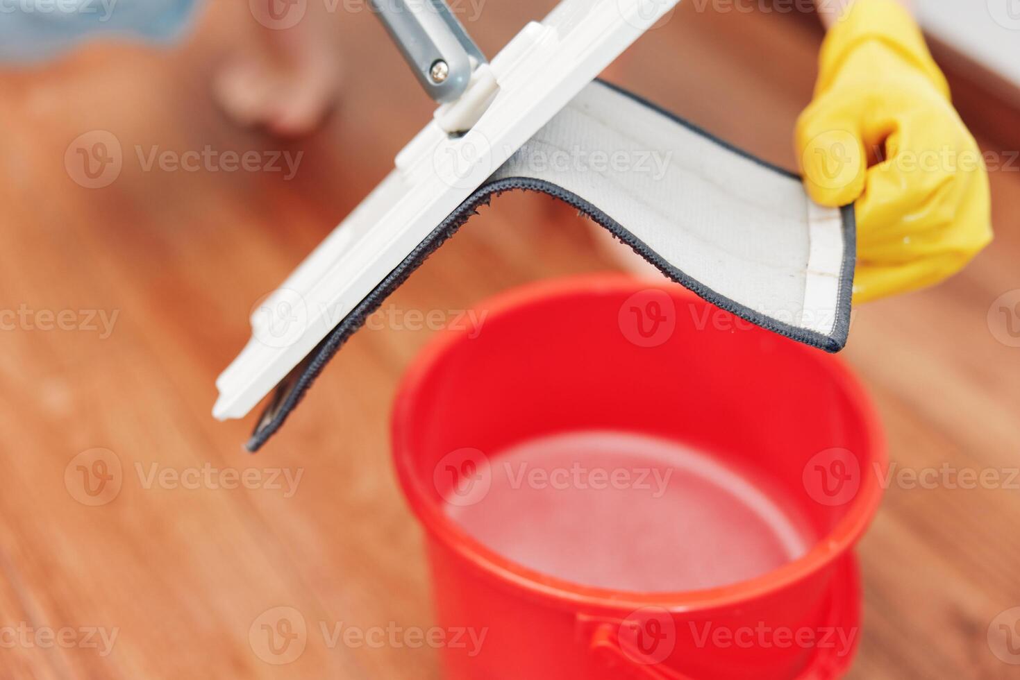 Woman cleaning wooden floor with mop, buckets of water nearby. housework concept. photo