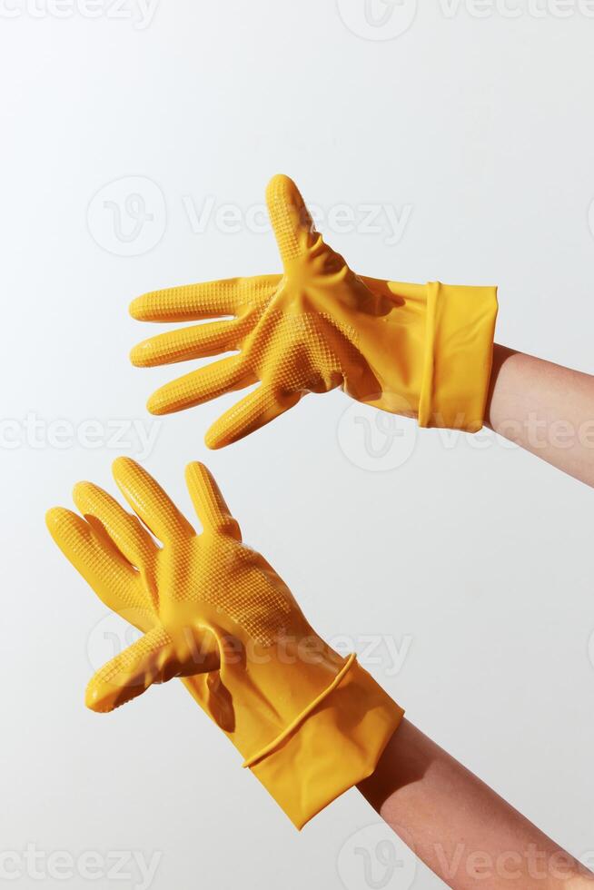 Yellow rubber gloves on white background, one person holding them out while the other reaches for photo