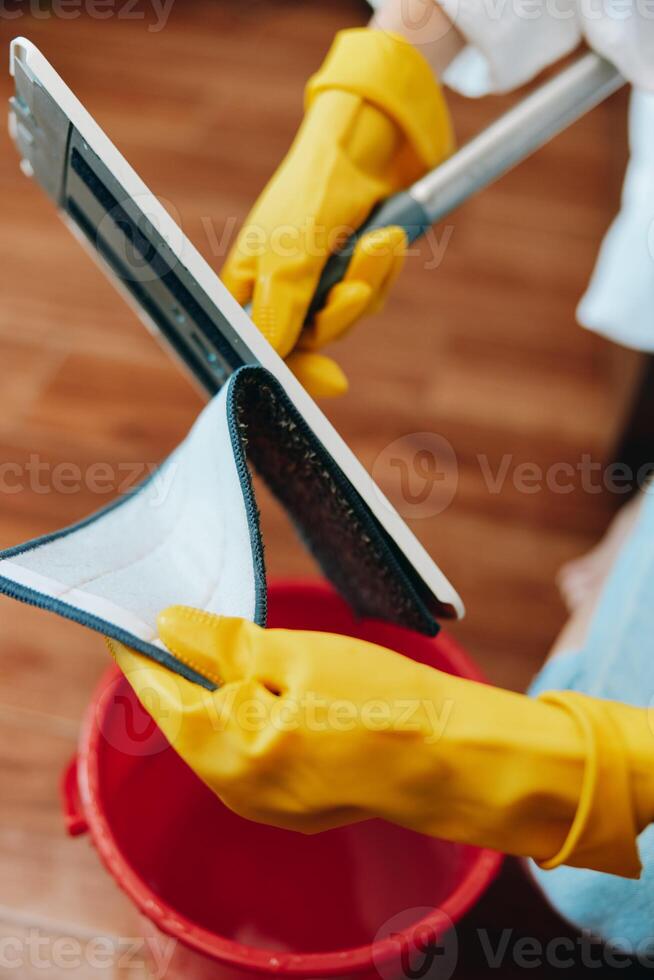Cleaning tablet with mop, person in yellow gloves, bucket of water and red rag. photo