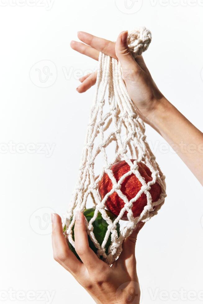 Green apple on white background in person's hand holding a white cotton bag. photo
