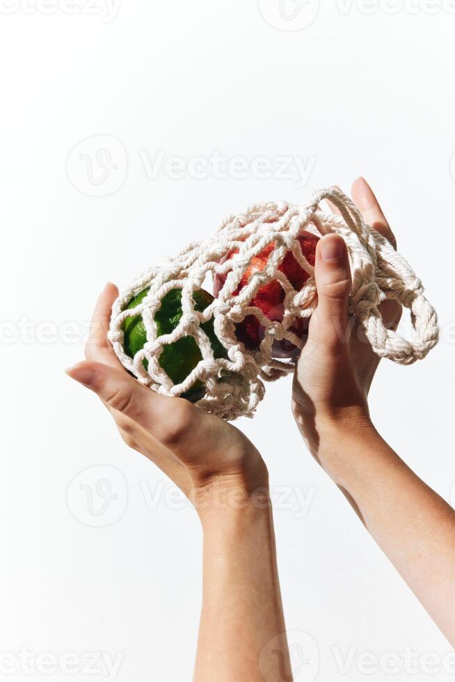 Hand holding knitted bag with green and red apples on white background. photo