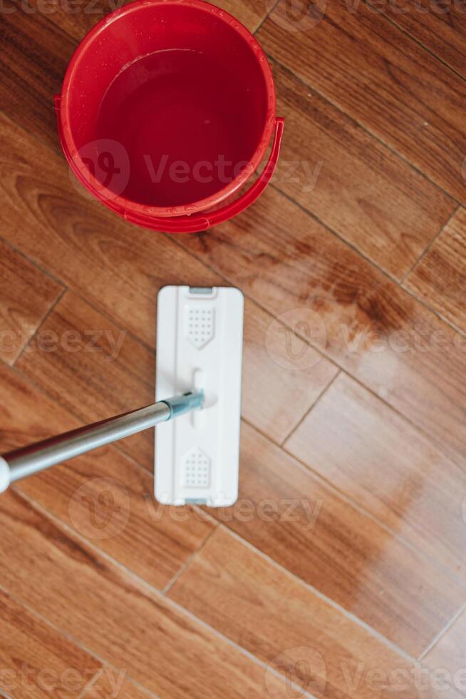 Cleaning hardwood floor with mop and bucket of water. a person is scrubbing the floor to remove dirt photo