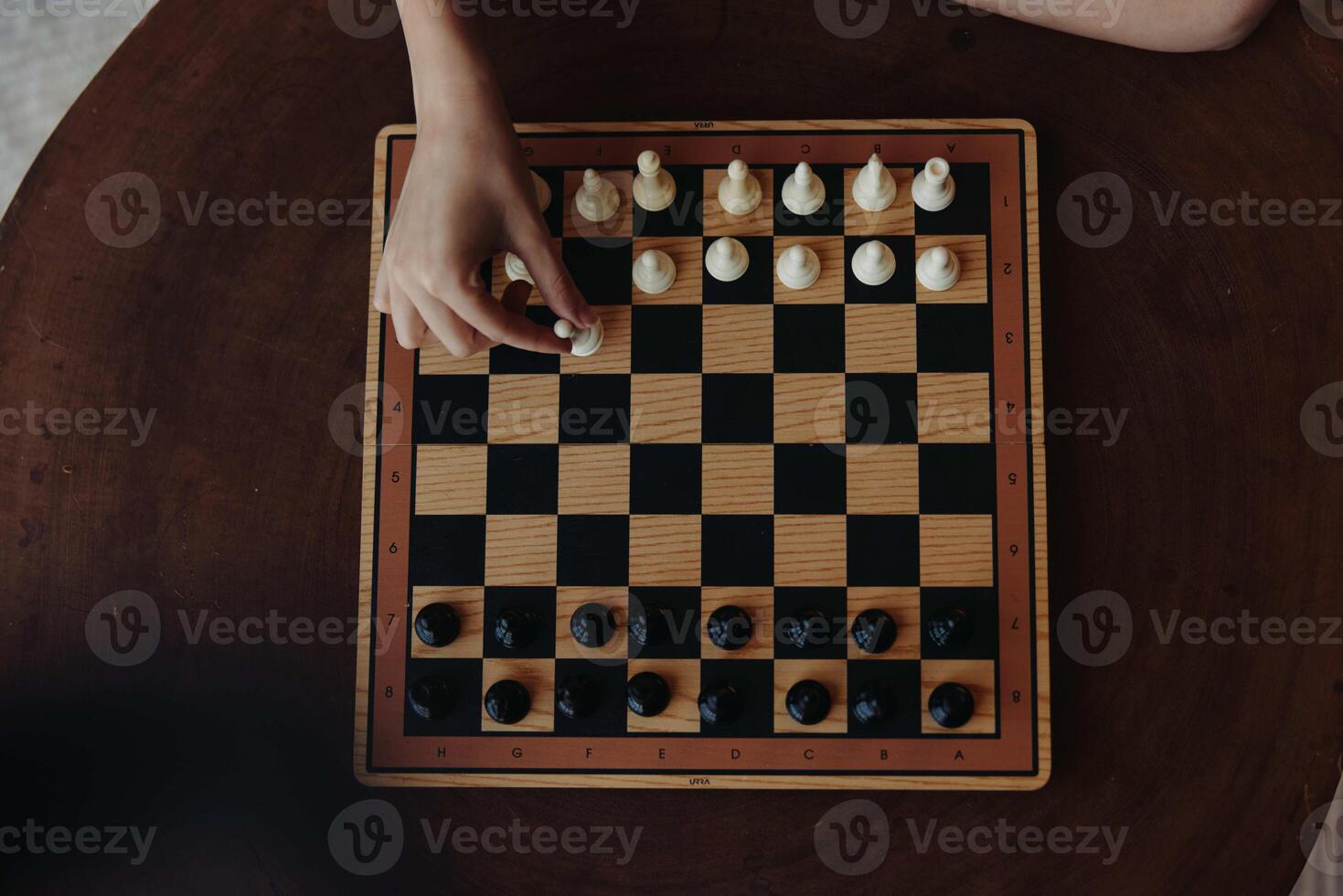 Person engaging in an intense game of strategy on a wooden table with a classic black and white photo