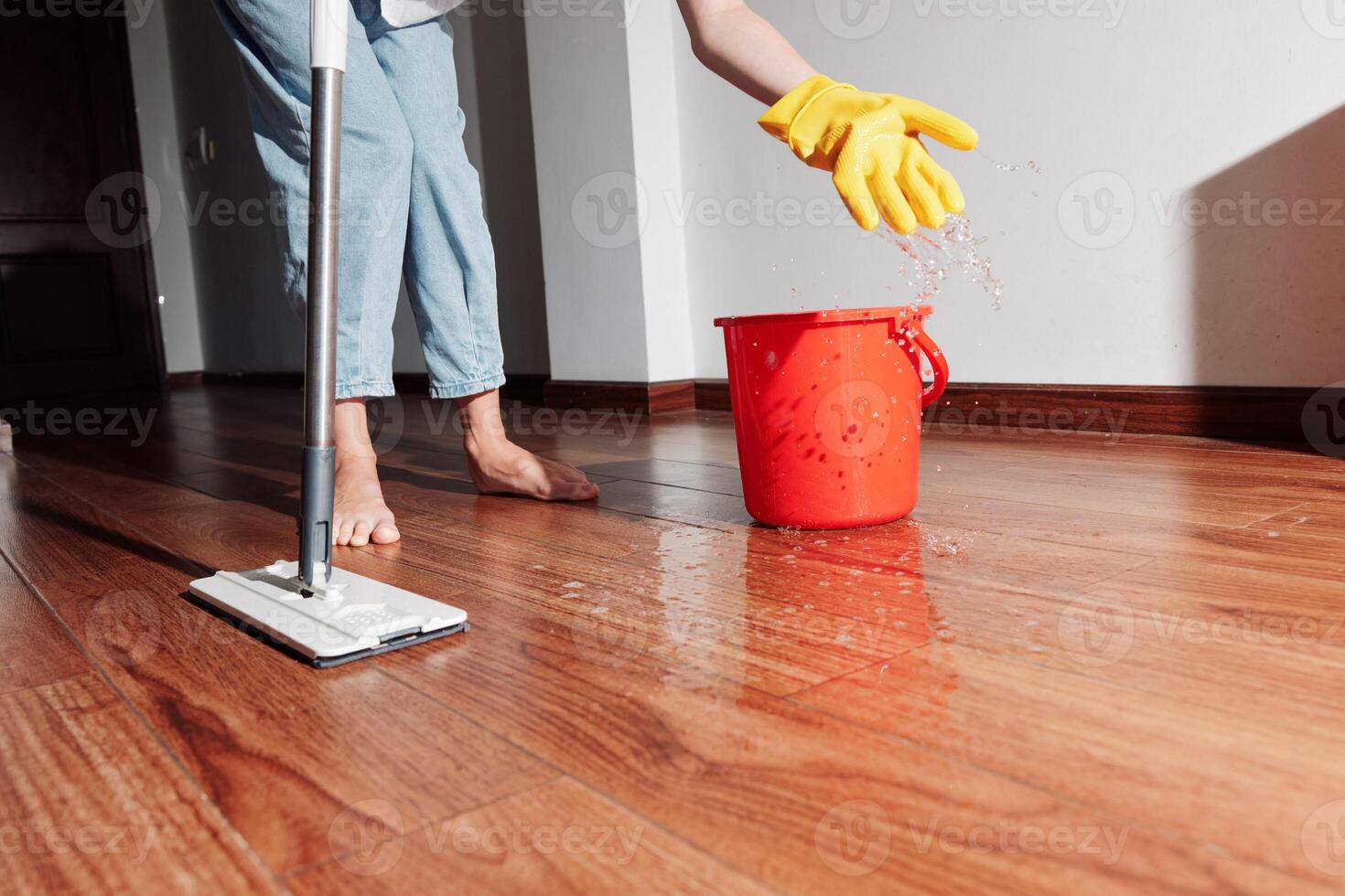Woman cleaning wooden floor with mop and bucket of water. household chores concept. photo