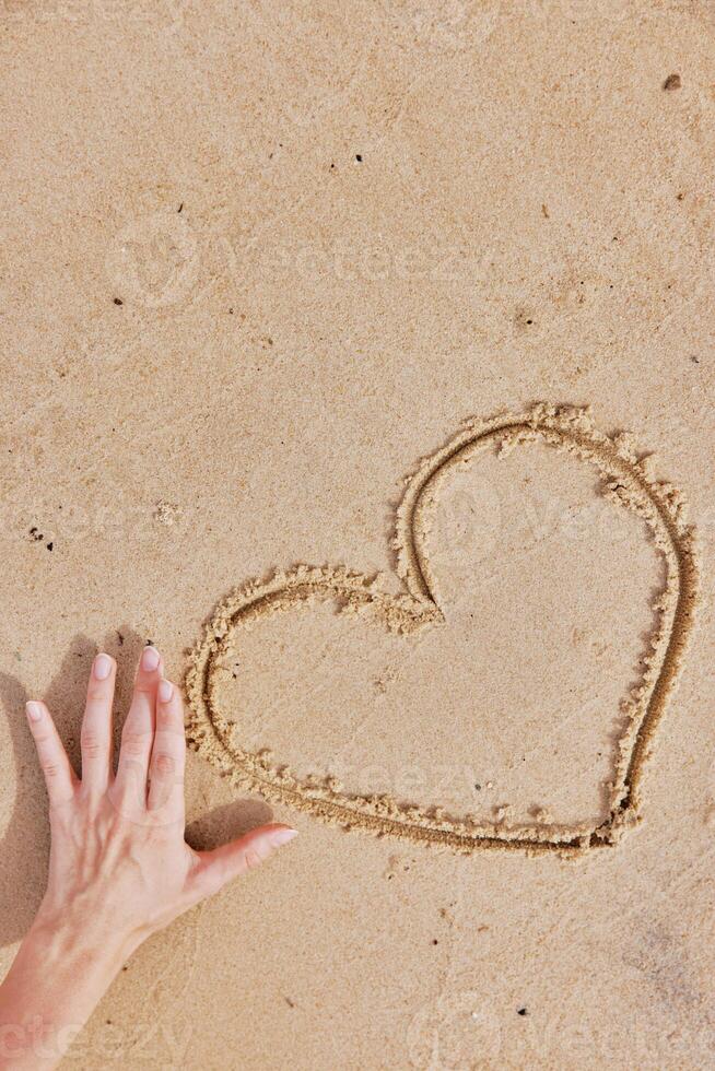Hand drawn heart shape in the sand on a beach next to an existing heart shape. romantic and creative photo