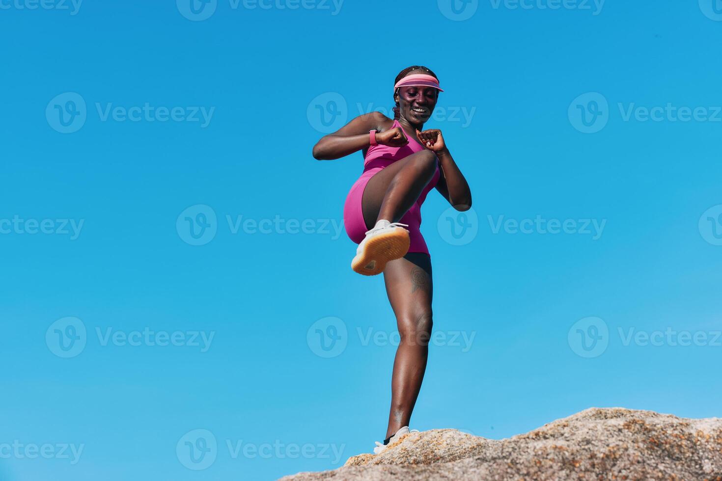 A confident athlete in pink sportswear performing a dynamic exercise outdoors, showcasing strength photo