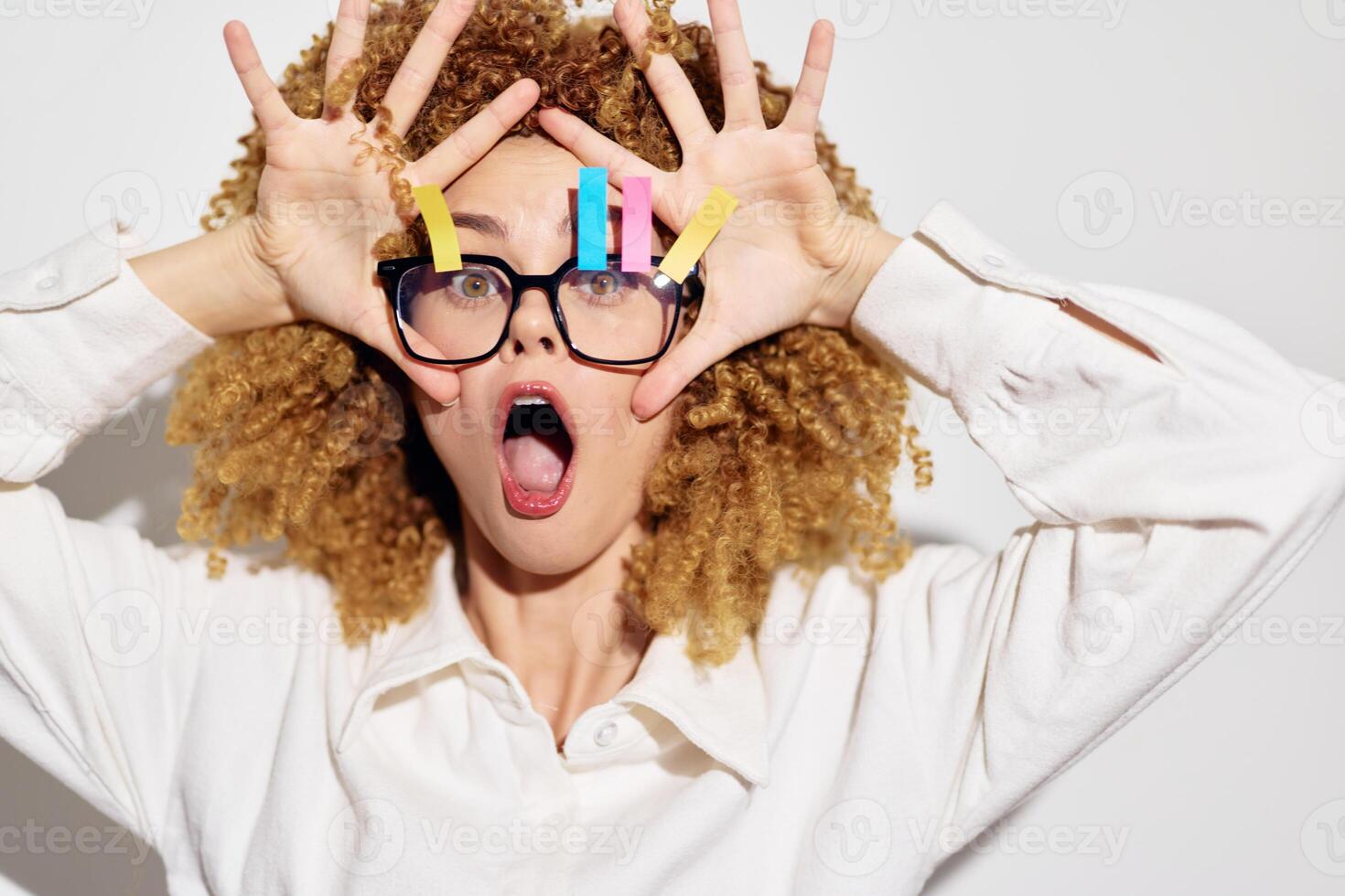 A surprised woman with curly hair holds her hands to her face, showcasing colorful clips The neutral photo