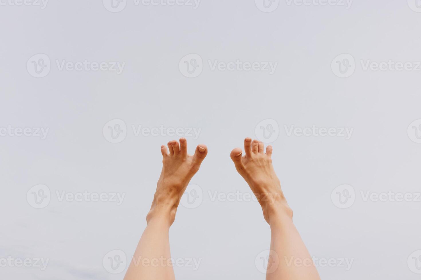 Bare feet raised against a blue sky, legs up in the air. a relaxing and carefree image of feet photo