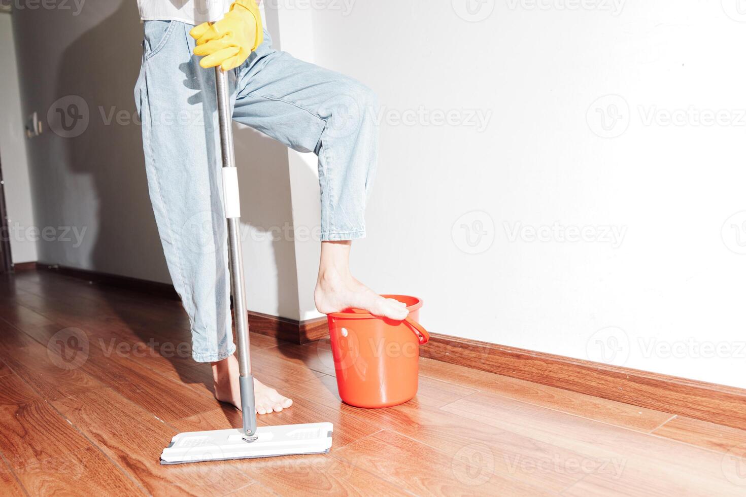Woman cleaning wooden floor with bucket and mop nearby. housework and cleaning concept. hardwood photo
