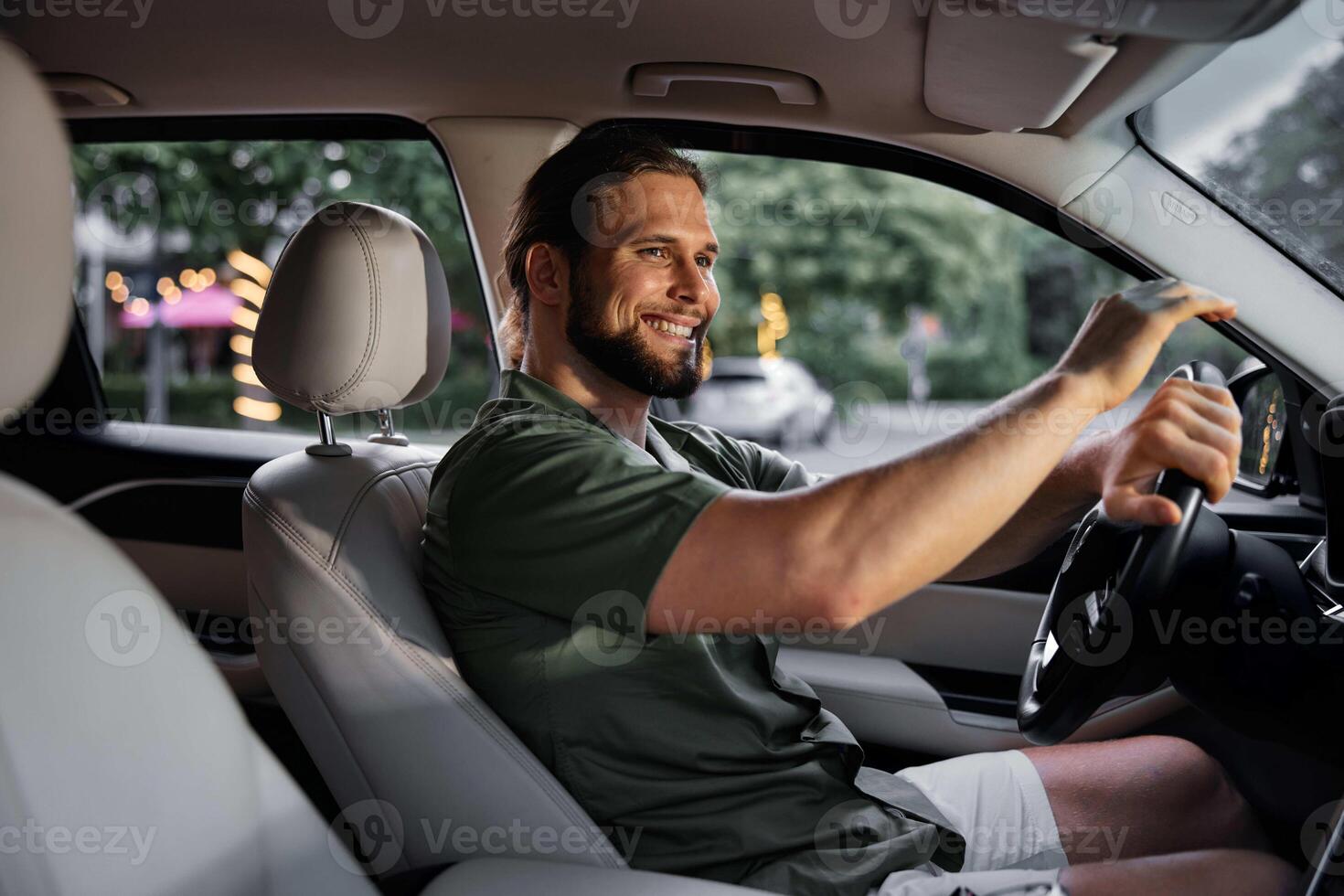 A cheerful man is seated in the driver s seat of a stylish car, surrounded by soft evening lights photo