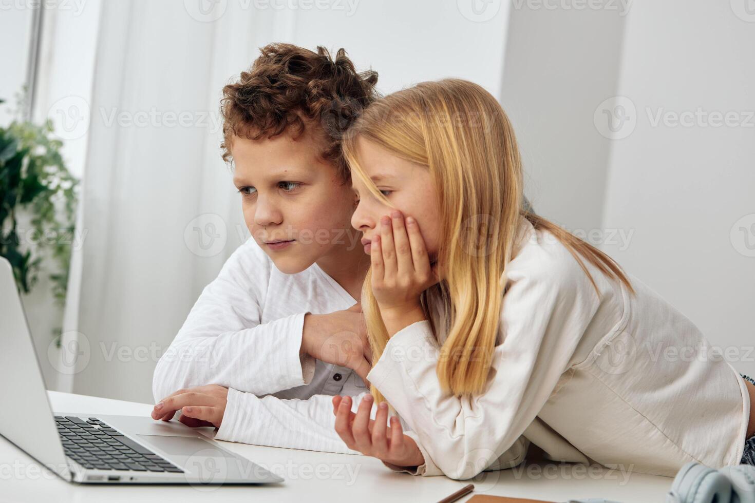 Boy and girl sitting at a table with a laptop, engaged in online education They are happy and photo