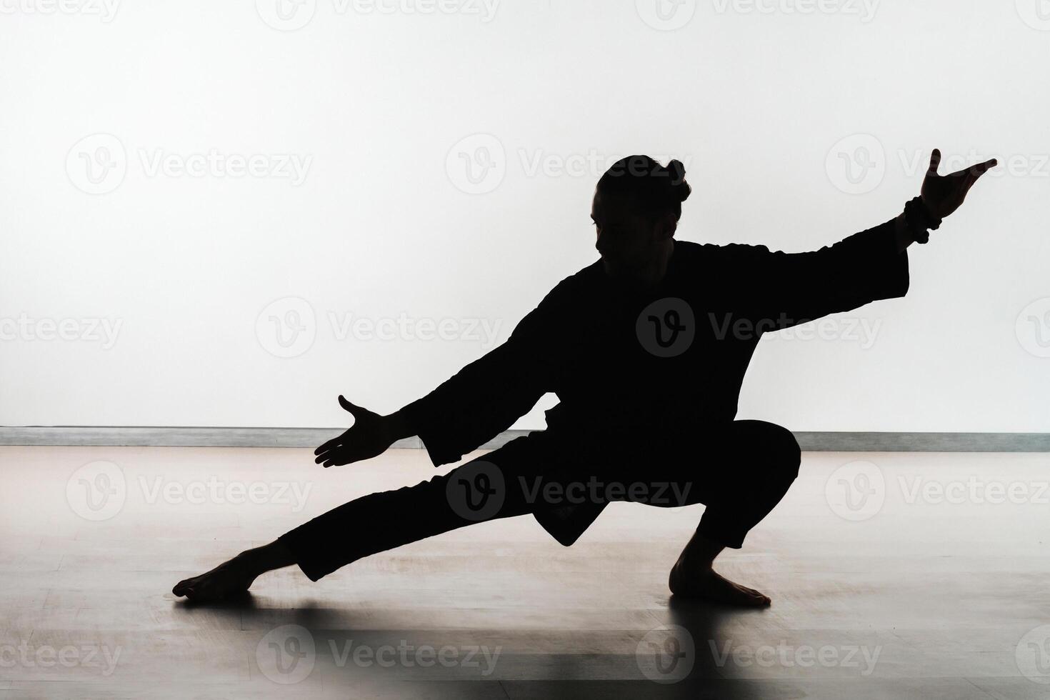 Silhouette of a person practicing qigong energy exercises on a light background photo