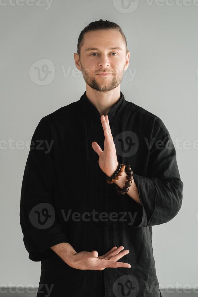 A man in black kimano practicing qigong energy exercises indoors photo