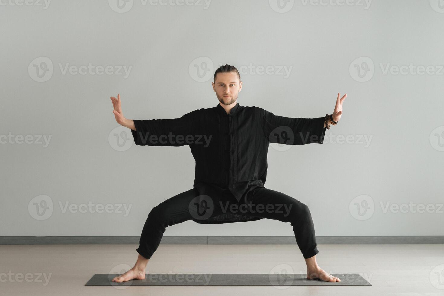 A man in black kimano practicing qigong energy exercises indoors photo