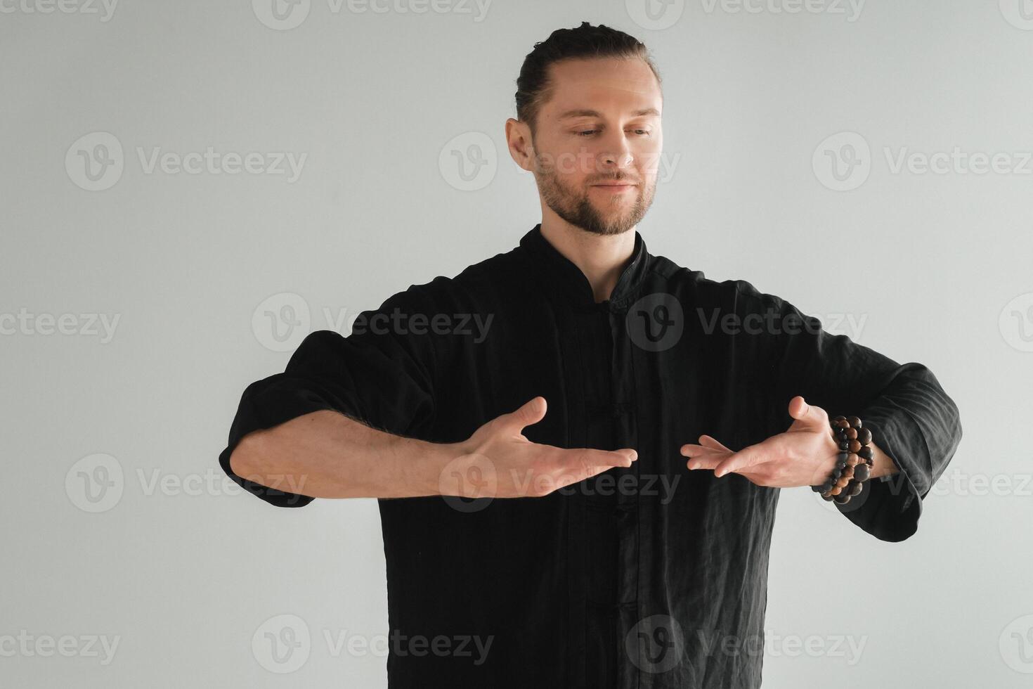 A man in black kimano practicing qigong energy exercises indoors photo