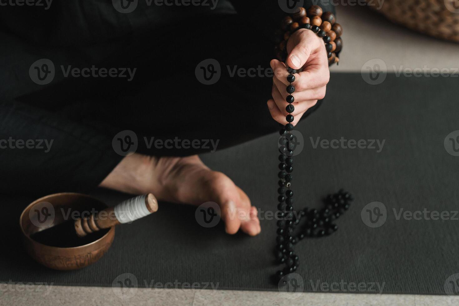 close-up of a man in a black kimono sitting in a lotus position on a gym mat in the interior photo