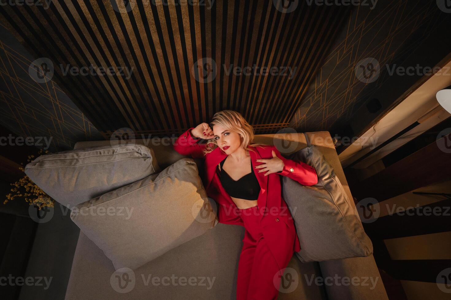 a beautiful girl dressed in a red formal suit posing in a modern interior photo
