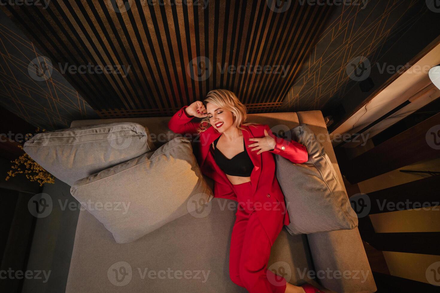 a beautiful girl dressed in a red formal suit posing in a modern interior photo