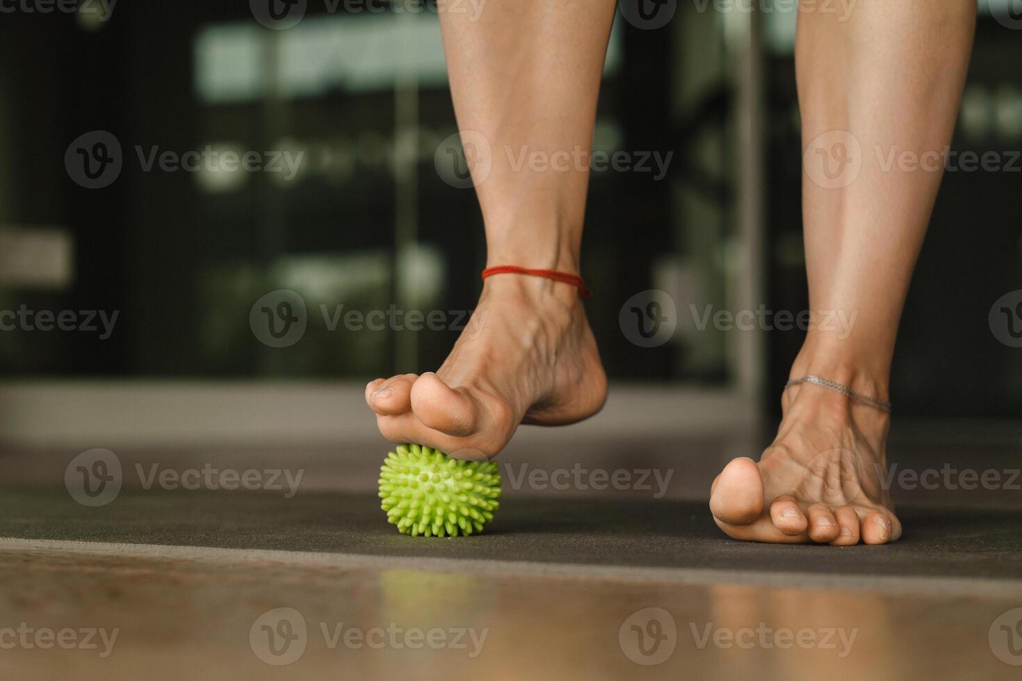 Close - up of the legs of a woman performing gymnastic exercises to correct flat feet during ball massage at home photo