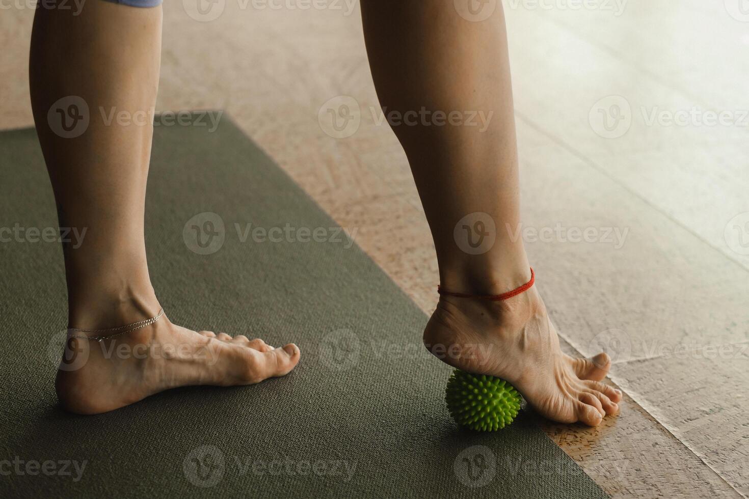 Close - up of the legs of a woman performing gymnastic exercises to correct flat feet during ball massage at home photo